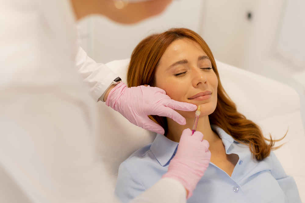 Facial plastic surgeon injecting lip filler into female patient