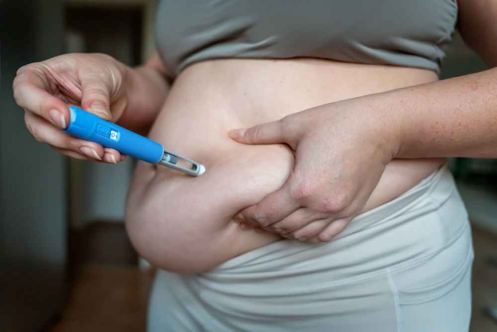 Woman injecting Ozempic, a GLP-1 weight loss medication, into her belly fat