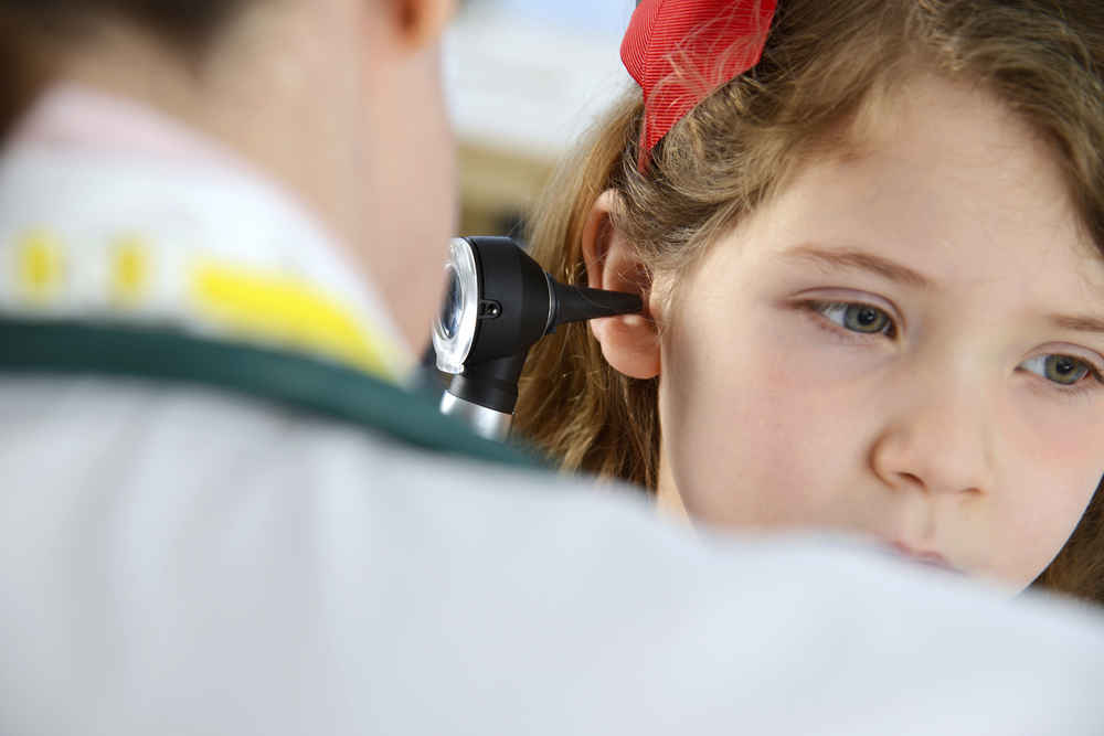 ENT doctor examining young child's ear