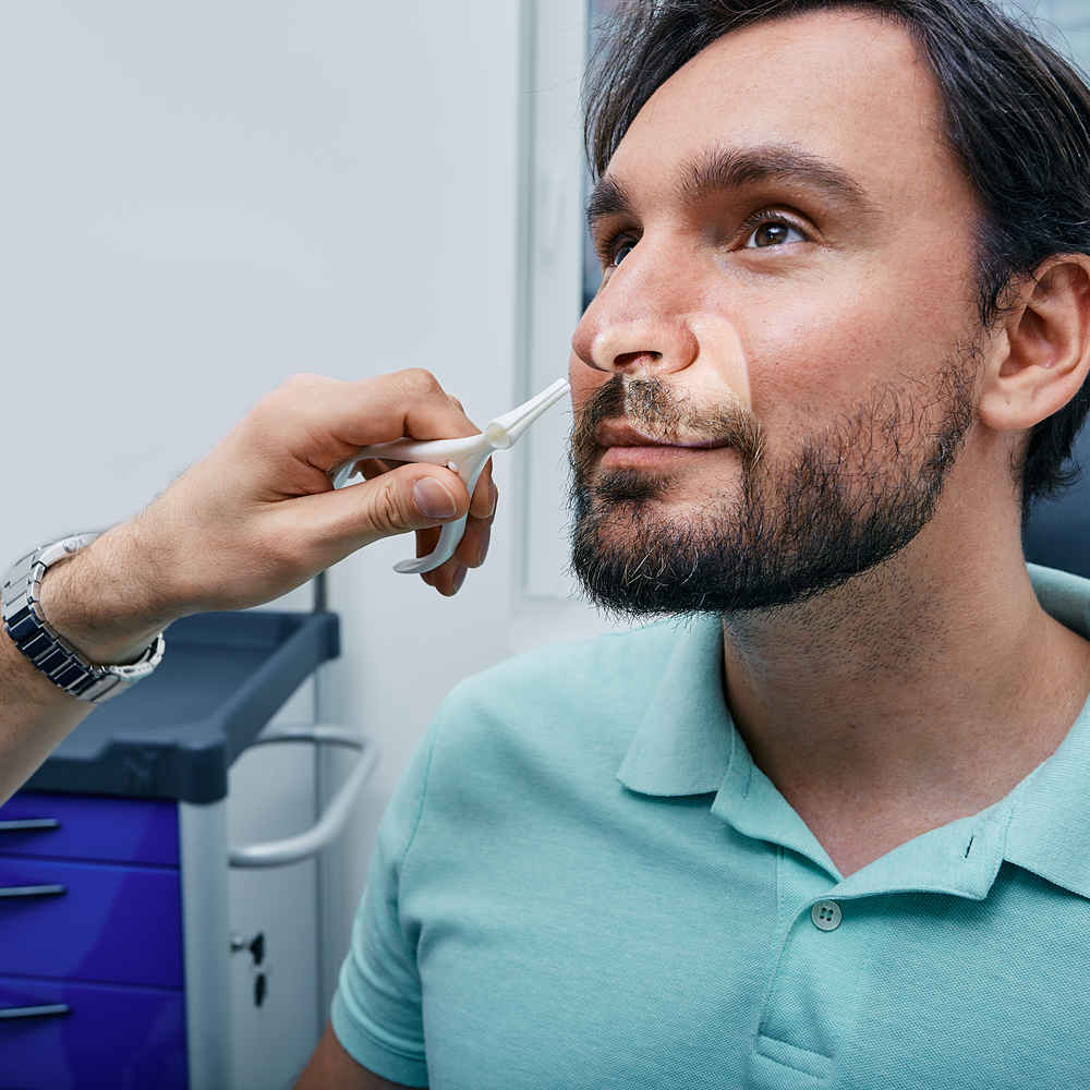 ENT doctor using a nasal speculum to examine patient's nose