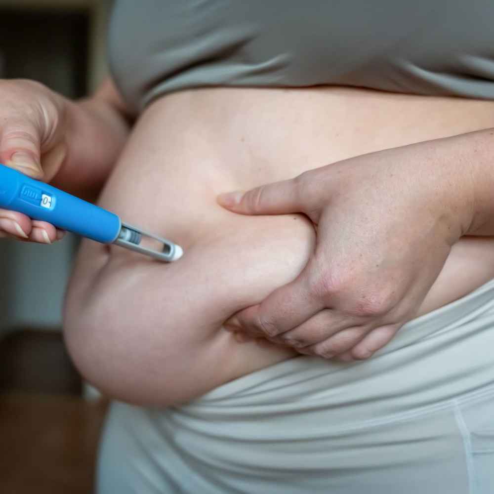 Woman injecting Ozempic, a GLP-1 weight loss medication, into her belly fat
